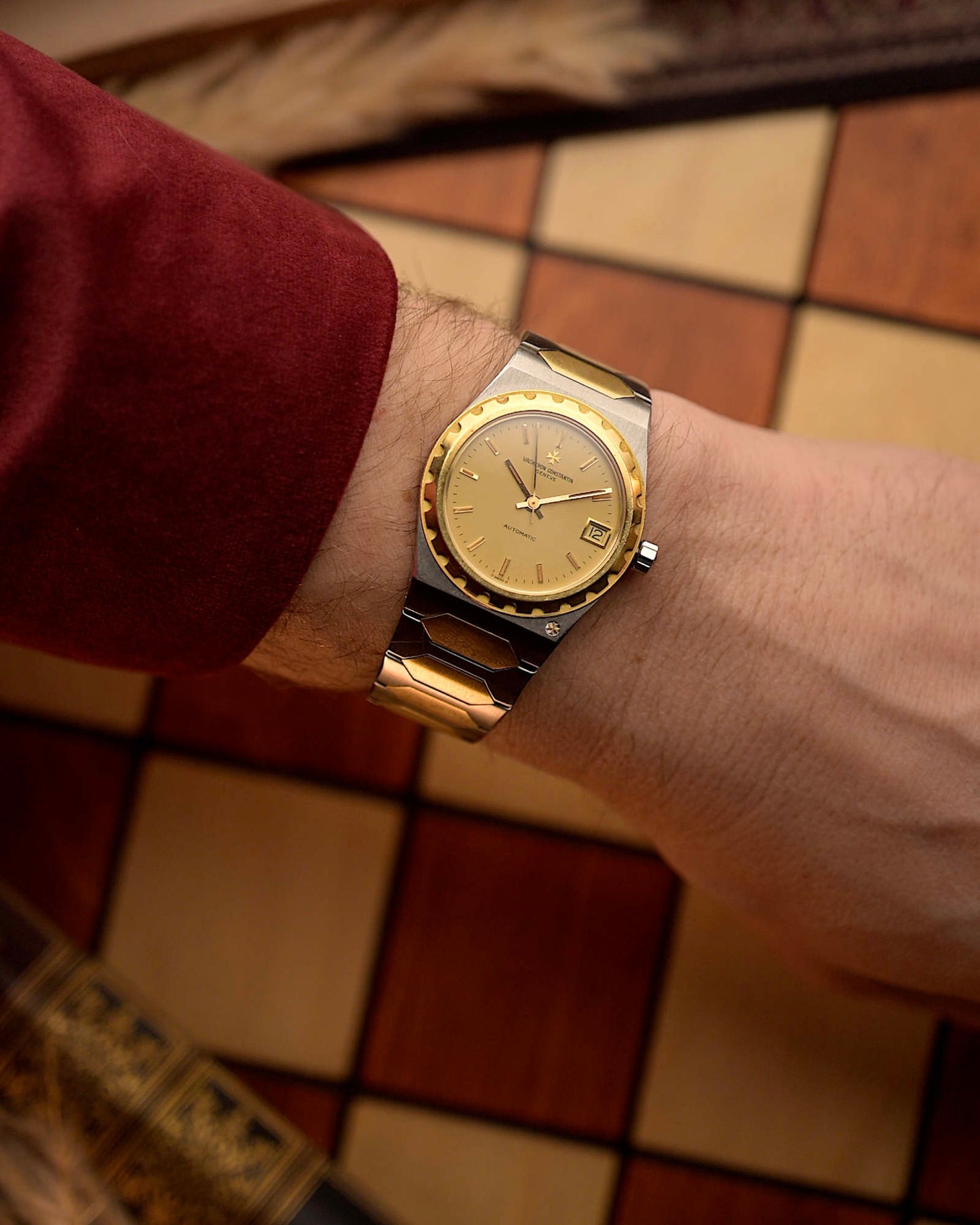 Vacheron Constantin 222 Ref 46003 Vintage watch from the 1980s, two-tone steel and 18k gold, golden Sigma dial, automatic movement on a person's wrist with a checkered floor background