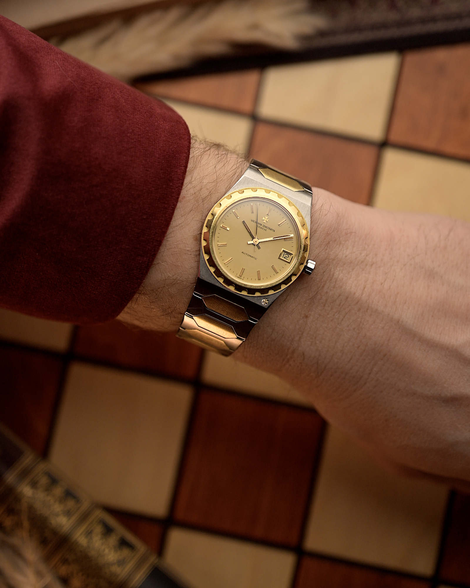 Vacheron Constantin 222 Ref 46003 Vintage watch from the 1980s, two-tone steel and 18k gold, golden Sigma dial, automatic movement on a person's wrist with a checkered floor background