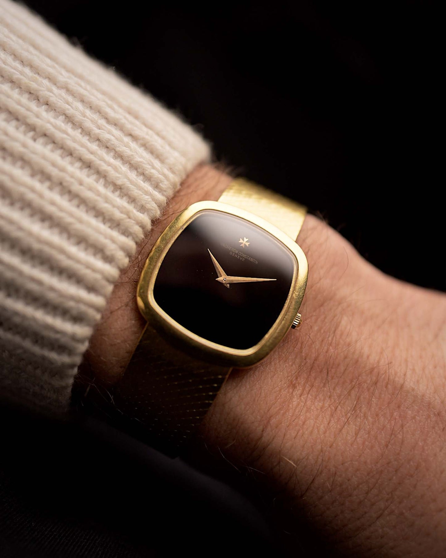 Vacheron Constantin 2099 Cushion Vintage watch from the 1970s, 18k yellow gold, Onyx dial, cushion case, on a wrist on black background