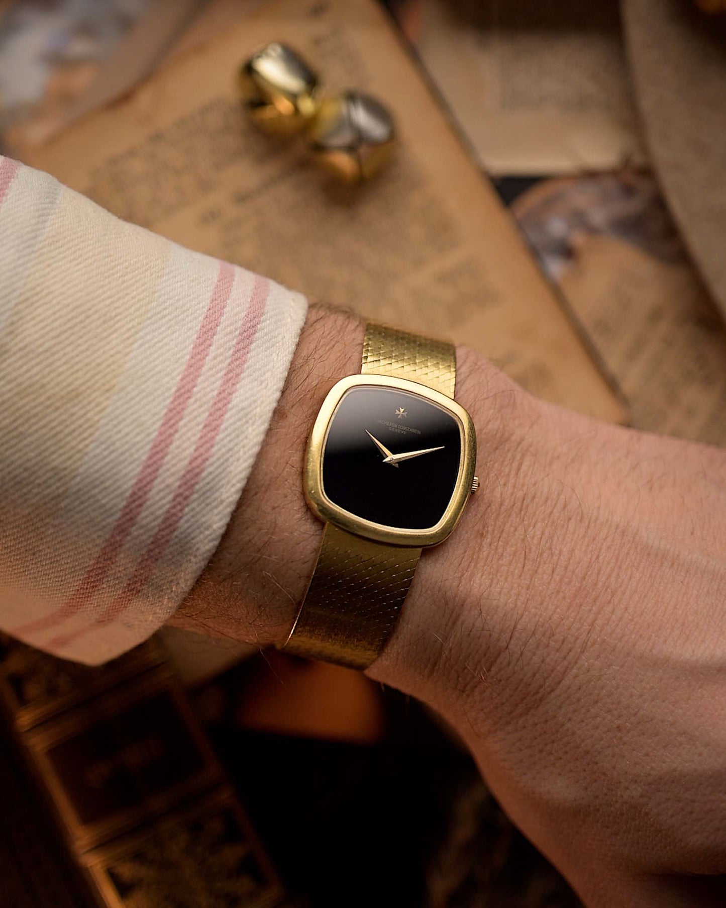 Vacheron Constantin 2099 Cushion Vintage watch from the 1970s, 18k yellow gold, Onyx dial, cushion case, on a wrist on blurred background